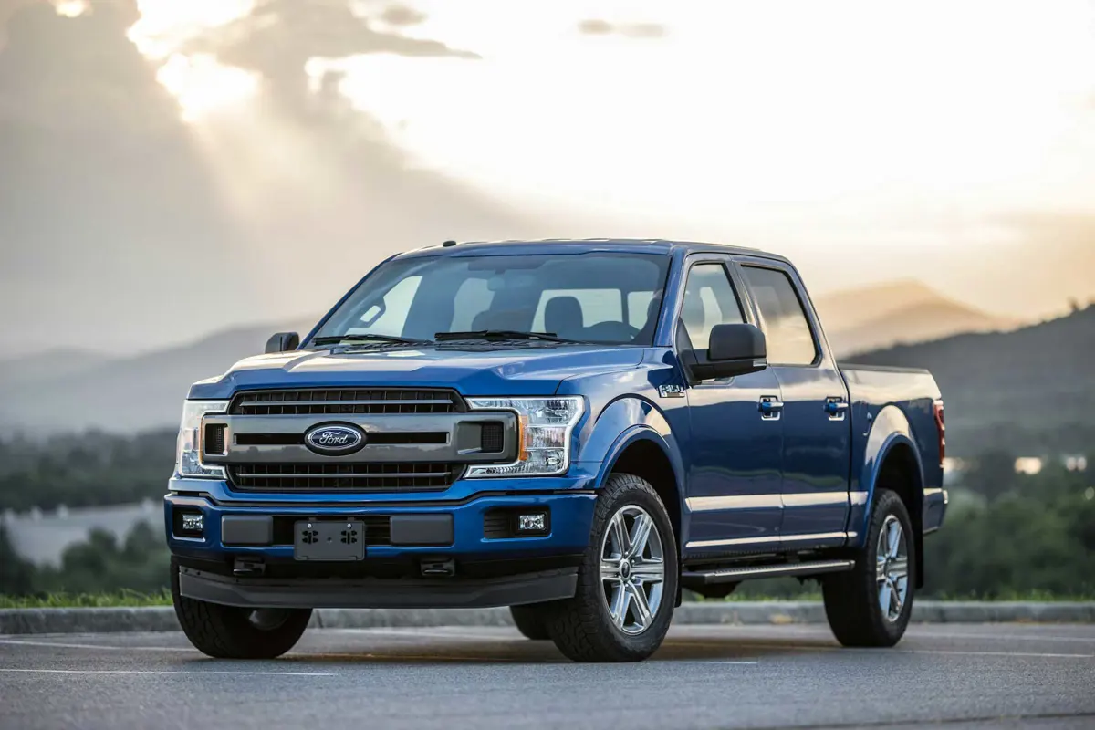 Blue Ford F-150 pickup truck parked outdoors with mountains and dramatic sky in the background